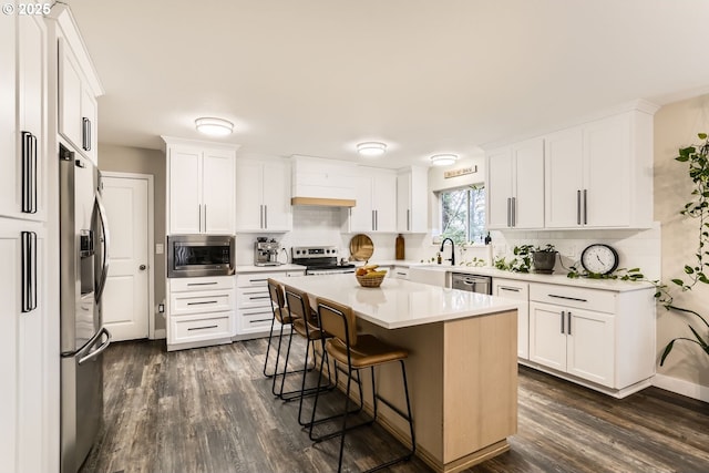 kitchen with a breakfast bar, a center island, white cabinetry, and appliances with stainless steel finishes