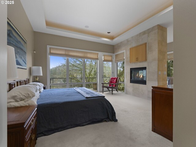 carpeted bedroom featuring a raised ceiling and a fireplace