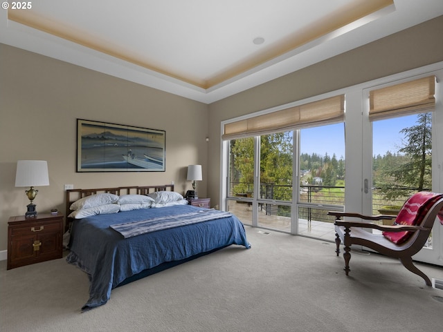 carpeted bedroom with a tray ceiling and access to outside