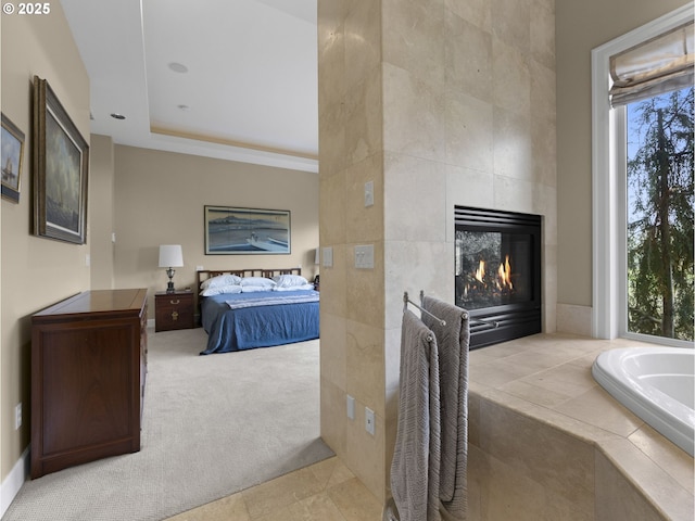 carpeted bedroom with multiple windows, a tray ceiling, and a fireplace