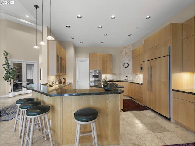 kitchen with tasteful backsplash, a breakfast bar, kitchen peninsula, paneled fridge, and light brown cabinets