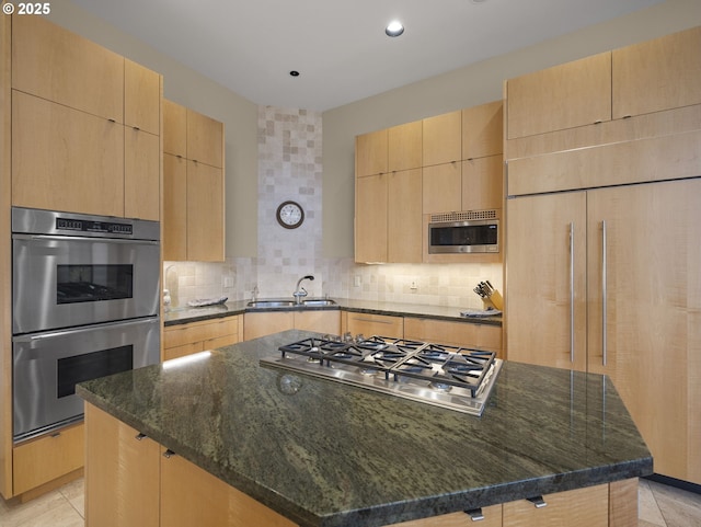 kitchen featuring sink, dark stone countertops, built in appliances, and a center island