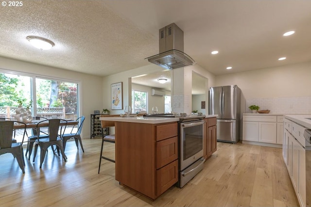 435 E 53rd Ave, Eugene, OR 97405 - kitchen with appliances with stainless steel finishes, island range hood, light wood-type flooring, a kitchen breakfast bar, and recessed lighting