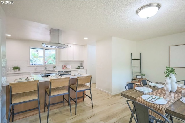 435 E 53rd Ave, Eugene, OR 97405 - kitchen featuring a kitchen breakfast bar, light wood-type flooring, white cabinetry, a textured ceiling, and light countertops