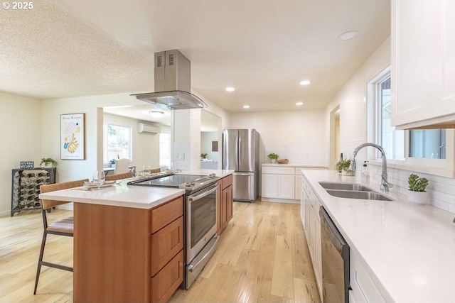 435 E 53rd Ave, Eugene, OR 97405 - kitchen featuring appliances with stainless steel finishes, island range hood, a breakfast bar area, light wood finished floors, and an AC wall unit