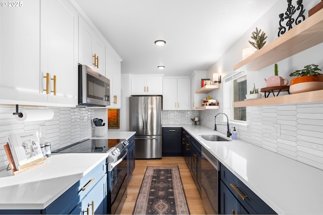 kitchen with white cabinetry, stainless steel appliances, decorative backsplash, sink, and blue cabinetry