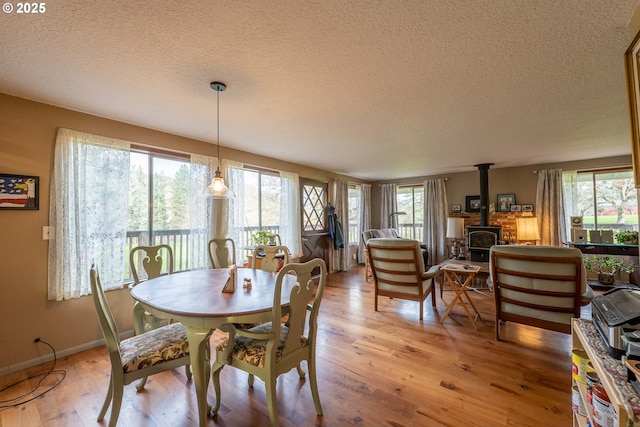 5383 Sunshine Rd, Roseburg, OR 97470 - dining space with a wood stove, light wood-style flooring, a textured ceiling, and baseboards