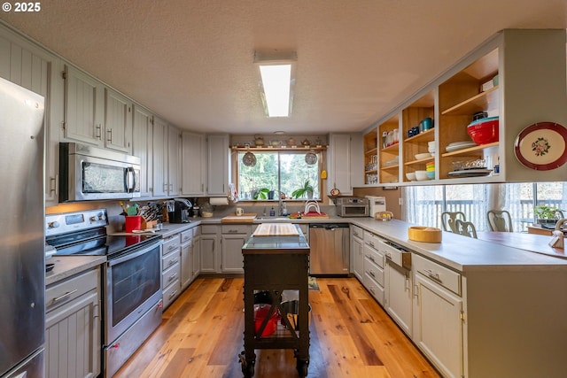 5383 Sunshine Rd, Roseburg, OR 97470 - kitchen with light wood-style flooring, open shelves, a peninsula, and stainless steel appliances