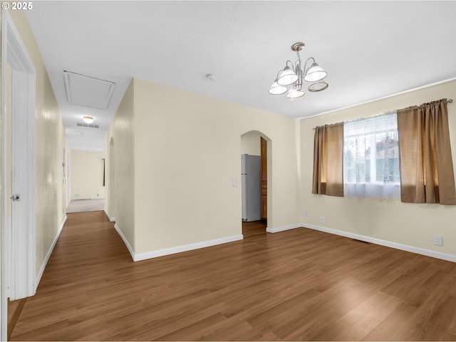 125 SW Cedar Ave, Warrenton, OR 97146 - unfurnished room featuring arched walkways, attic access, wood finished floors, a chandelier, and a smoke detector