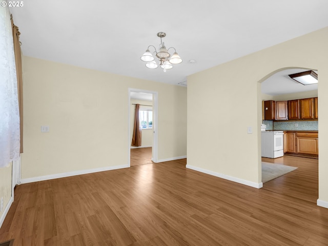 125 SW Cedar Ave, Warrenton, OR 97146 - unfurnished living room with arched walkways, wood finished floors, and a chandelier