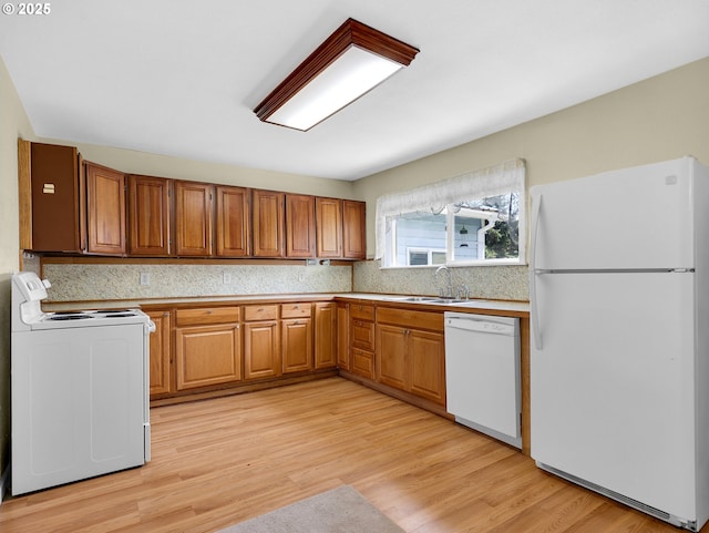 125 SW Cedar Ave, Warrenton, OR 97146 - kitchen with white appliances, brown cabinetry, and light wood-style flooring