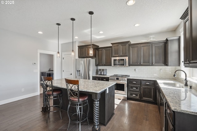 132 N 39th Ct, Ridgefield, WA 98642 - kitchen with stainless steel appliances, dark wood-type flooring, a center island, dark brown cabinetry, and backsplash