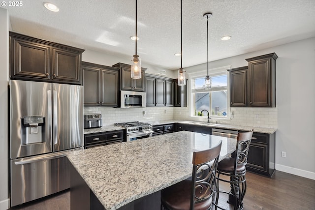 132 N 39th Ct, Ridgefield, WA 98642 - kitchen with stainless steel appliances, dark brown cabinets, dark wood finished floors, light stone counters, and a center island