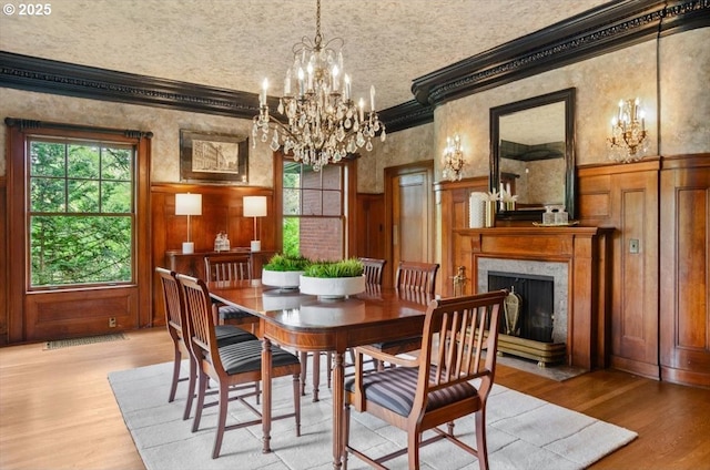 1965 SW Montgomery Pl, Portland, OR 97201 - dining area featuring a chandelier, ornamental molding, light wood-style flooring, a premium fireplace, and wainscoting