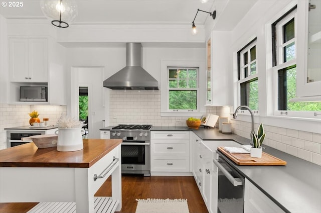 1965 SW Montgomery Pl, Portland, OR 97201 - kitchen with wooden counters, wall chimney range hood, stainless steel appliances, decorative backsplash, and ornamental molding