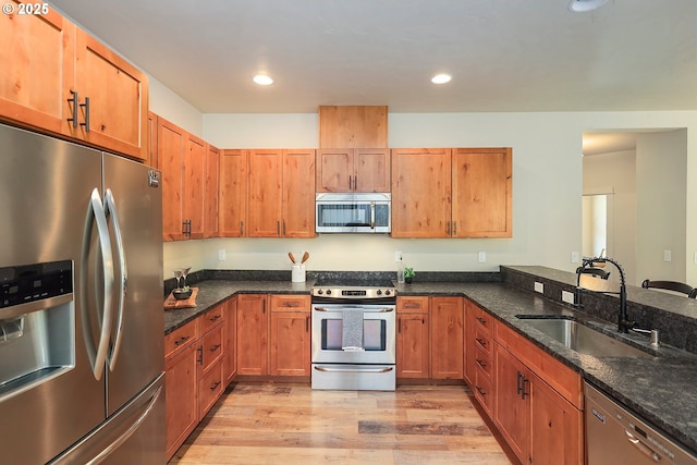 kitchen with light wood-style flooring, recessed lighting, a sink, stainless steel appliances, and dark stone counters
