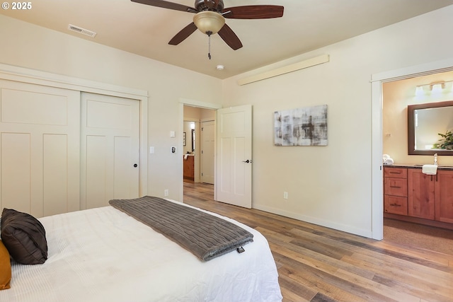 bedroom with light wood-style flooring, a closet, visible vents, baseboards, and ensuite bath