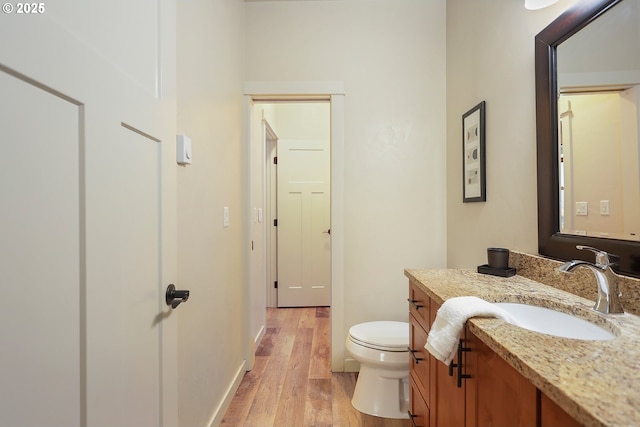 bathroom featuring toilet, baseboards, vanity, and wood finished floors