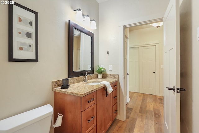 bathroom featuring toilet, wood finished floors, and vanity