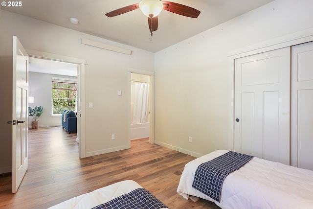 bedroom with a closet, light wood-style flooring, baseboards, and ceiling fan
