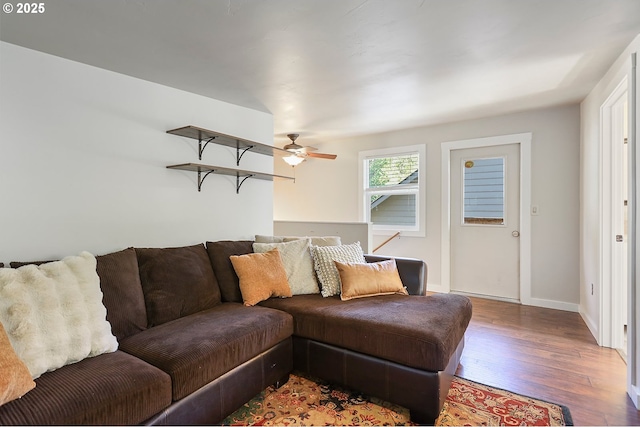 living room with ceiling fan, baseboards, and wood finished floors