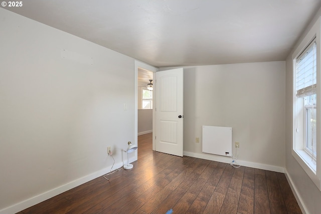 unfurnished room with baseboards, radiator, and dark wood-style floors