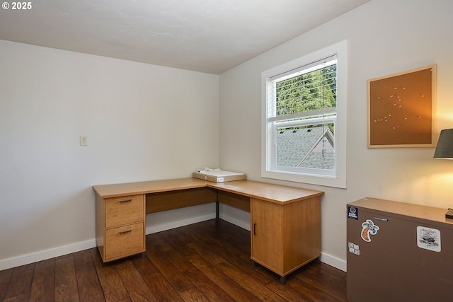 unfurnished office with built in desk, baseboards, and dark wood-type flooring