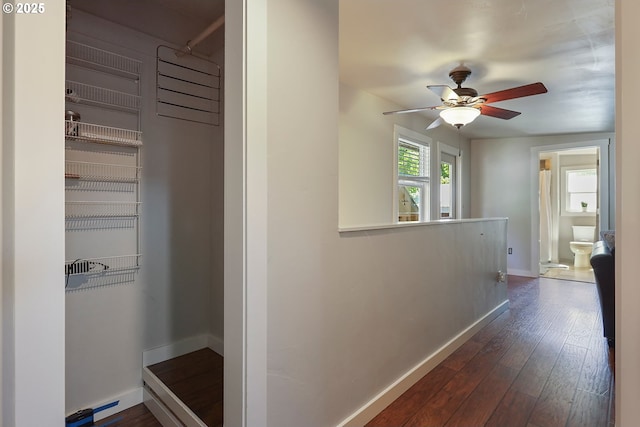 corridor featuring baseboards and dark wood-type flooring