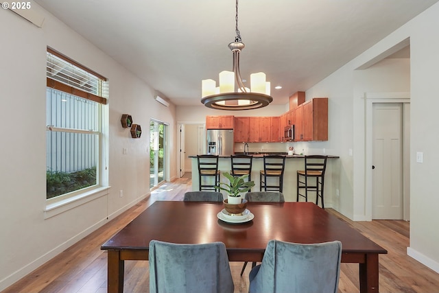 dining area with light wood-style flooring, a chandelier, baseboards, and recessed lighting