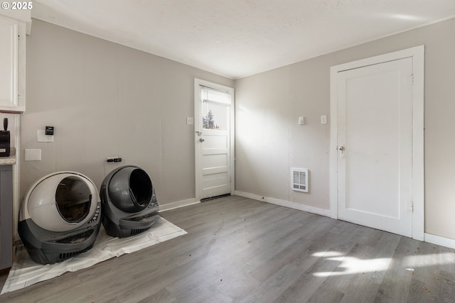 laundry room featuring heating unit and light wood-type flooring