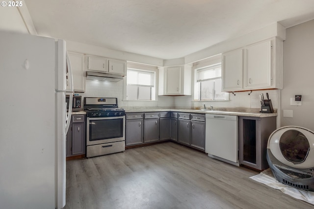 kitchen featuring sink, gray cabinetry, decorative backsplash, white appliances, and light hardwood / wood-style flooring