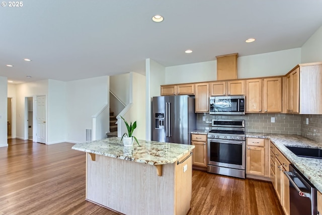 kitchen featuring appliances with stainless steel finishes, decorative backsplash, dark wood-style flooring, and a center island