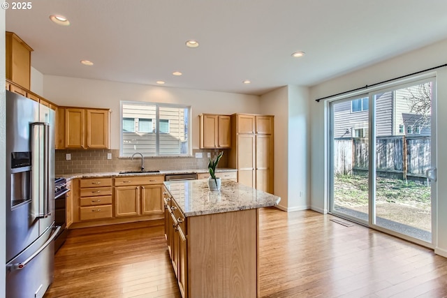 kitchen featuring plenty of natural light, decorative backsplash, appliances with stainless steel finishes, wood finished floors, and a sink