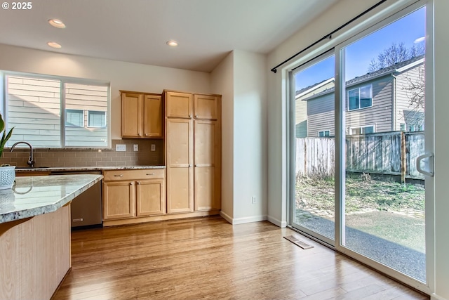 kitchen with visible vents, decorative backsplash, stainless steel dishwasher, a sink, and light wood-type flooring