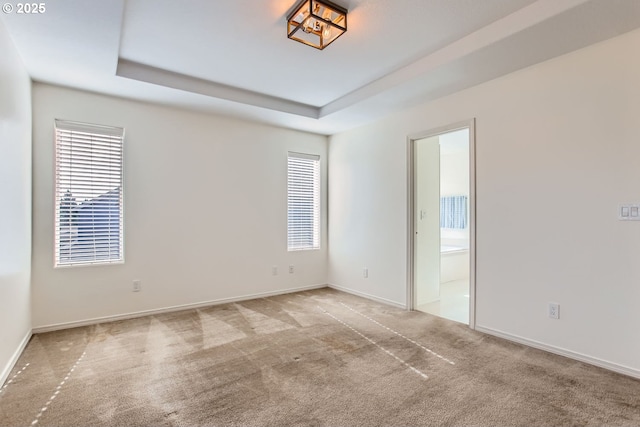 carpeted empty room with a raised ceiling and baseboards