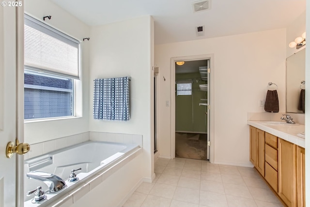 bathroom with tile patterned flooring, double vanity, visible vents, and a bath