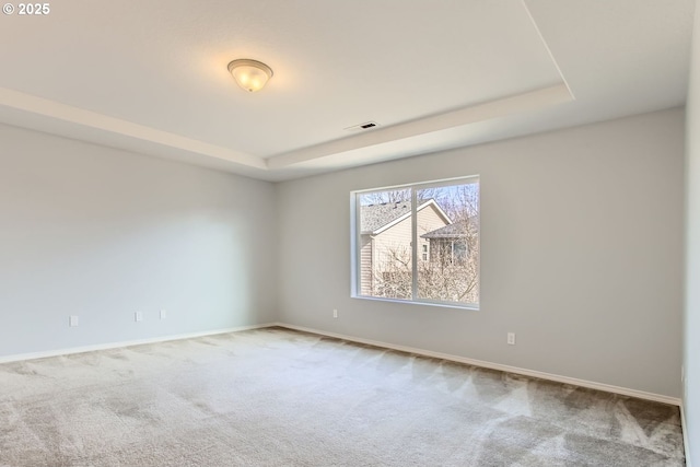 empty room featuring carpet floors, a tray ceiling, and visible vents