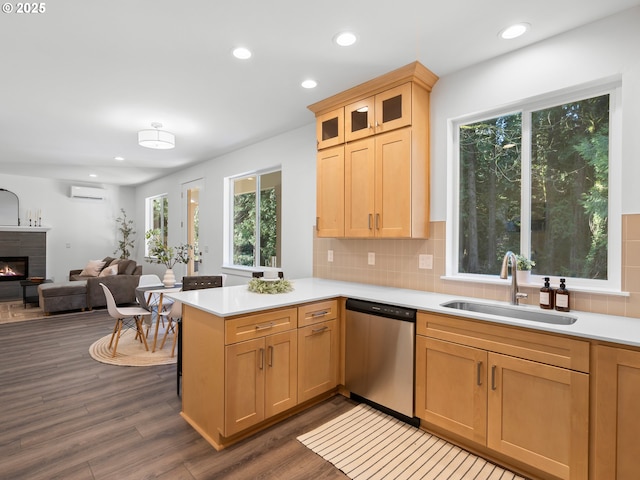 kitchen with a fireplace, dishwasher, sink, a wall mounted AC, and kitchen peninsula