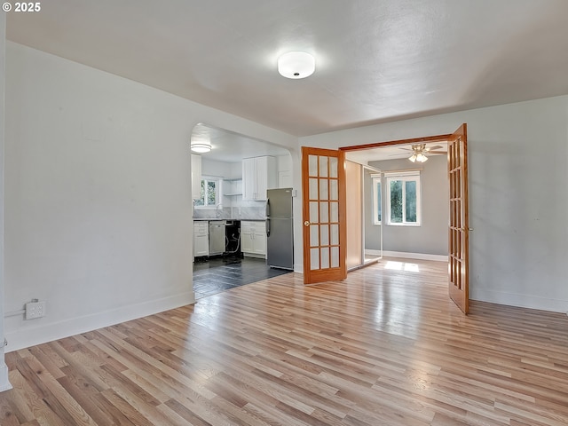 12226 SE Raymond St, Portland, OR 97236 - unfurnished living room featuring wood finished floors, baseboards, arched walkways, and ceiling fan