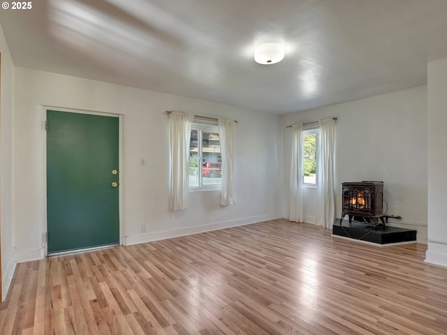 12226 SE Raymond St, Portland, OR 97236 - unfurnished living room featuring a wood stove, light wood finished floors, and baseboards