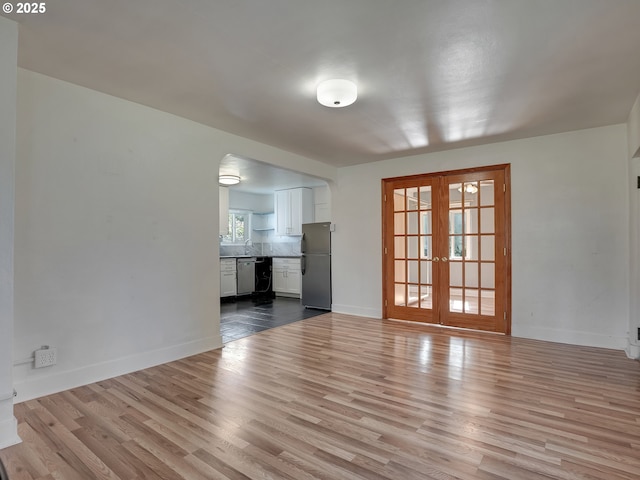 12226 SE Raymond St, Portland, OR 97236 - unfurnished living room featuring french doors, wood finished floors, baseboards, and arched walkways