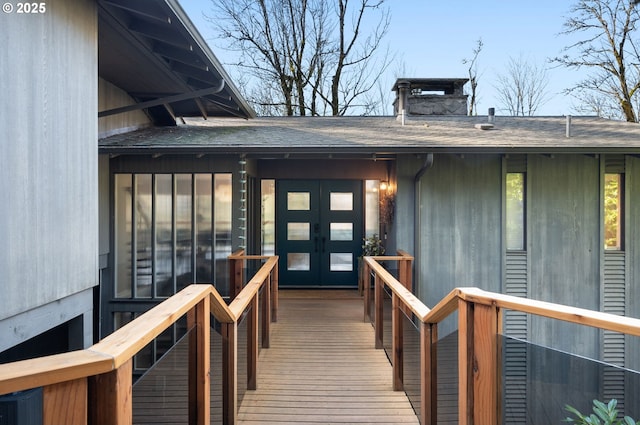 doorway to property with french doors, a chimney, and a shingled roof