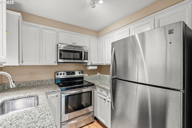 1726 Minda Dr Unit 1, Eugene, OR 97401 - kitchen featuring appliances with stainless steel finishes, white cabinets, and light stone countertops