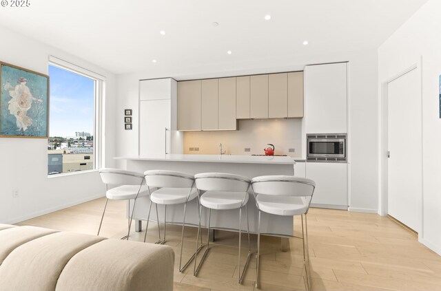 1150 NW Quimby St Unit 442, Portland, OR 97209 - kitchen featuring stainless steel microwave, light wood-style floors, modern cabinets, light countertops, and a kitchen island