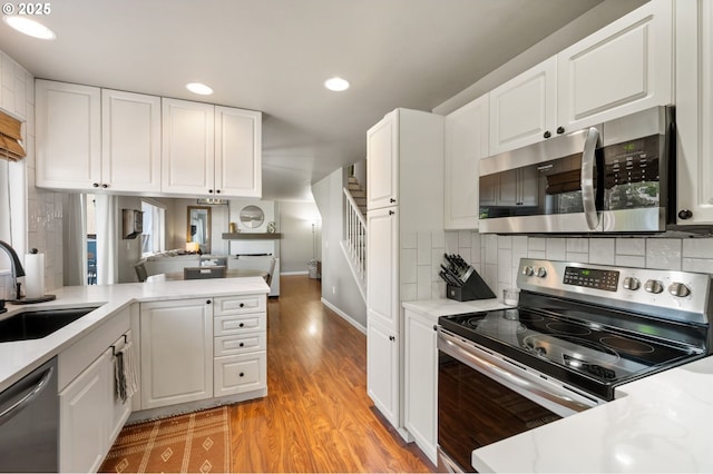 kitchen with stainless steel appliances, a sink, light countertops, recessed lighting, and tasteful backsplash