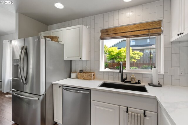 kitchen featuring a sink, stainless steel appliances, backsplash, white cabinetry, and recessed lighting