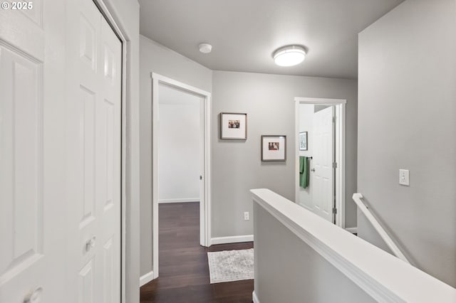 hallway featuring an upstairs landing, dark wood finished floors, and baseboards
