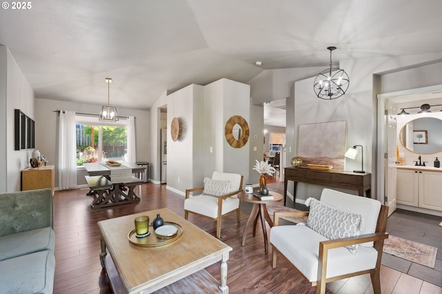 living room with vaulted ceiling, wood finished floors, a chandelier, and baseboards