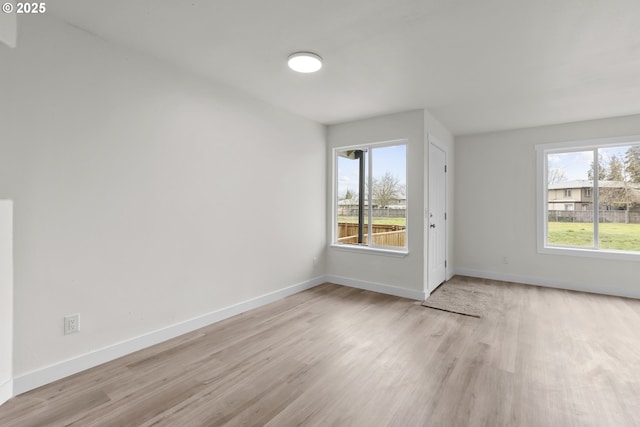 unfurnished room featuring light wood-style flooring, a wealth of natural light, and baseboards