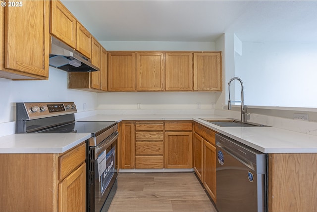 kitchen with light countertops, light wood-style flooring, appliances with stainless steel finishes, a sink, and under cabinet range hood